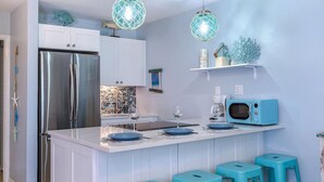 Een moderne keuken met een centraal eiland, een koelkast van roestvrij staal en blauwe accenten.