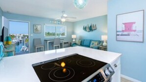 Een moderne keuken met een wit kookeiland, blauwe wanden en uitzicht op de oceaan.