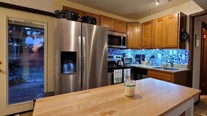 A modern kitchen with stainless steel appliances, wooden cabinets, and a patterned backsplash.