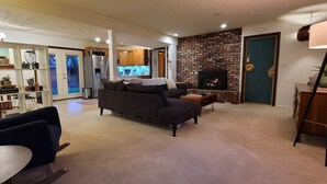 A living room with a dark-colored sofa, a coffee table, and a bookshelf filled with books and decorative items.