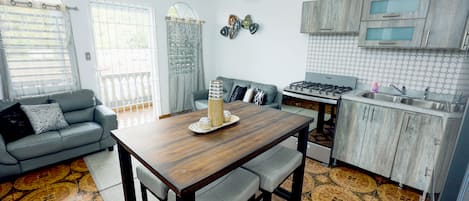 A modern kitchen with a dining table, grey sofa, and a kitchen island.