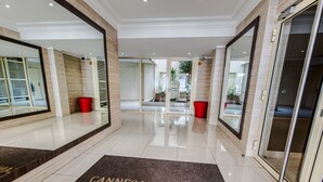 Un hall d’hôtel avec un sol ciré, un comptoir d’accueil et une porte dotée d’un panneau en verre.