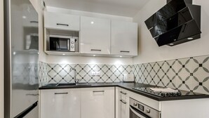 Une cuisine moderne avec des armoires blanches, un plan de travail noir, un four à micro-ondes, une cuisinière et un crédence décorée.