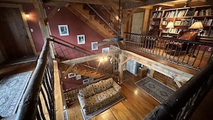 Interior de madeira com escada, um sofá e uma estante de livros.