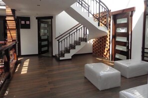 A modern interior with a wooden staircase, a fireplace, and a seating area with cushions.