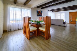 A dining area with a wooden table and chairs, a sofa, and a painting on the wall.