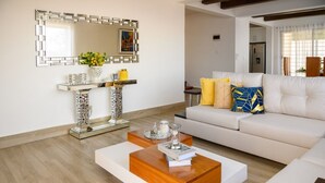 Un soggiorno moderno con un divano bianco, un tavolino in legno e uno specchio decorativo.