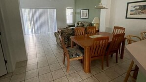A dining area with a wooden table and chairs, a ceiling fan, and a window with blinds. - 5 minues to the theme park. Family sized communy pool (Kissimmee)
