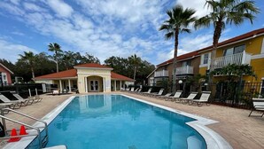 A swimming pool with lounge chairs and palm trees. - 5 minues to the theme park. Family sized communy pool (Kissimmee)