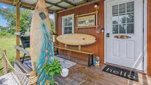 A wooden porch with surfboards, a bench, and a welcome sign. - Tiny Home Near the Bay by Beach's, Pensacola, Foley, Gulf Shores, Orange Beach
 (Elberta)