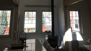 A spacious living room with a high ceiling, large windows, a chandelier, and a fireplace. - Two apartments in one house (Silverton)