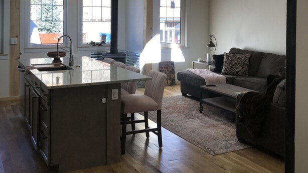 A spacious kitchen with a central island, a dining area with chairs, and a living room with a sofa and a coffee table. - Two apartments in one house (Silverton)