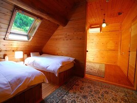 Acogedora habitación tipo cabaña con dos camas, una ventana y un ventilador de techo.