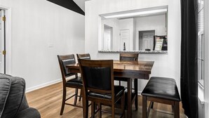 A dining area with a wooden table and chairs, a large mirror above the table, and a chandelier. - Midnight Lexington Newly Remodeled Designer Stay (Lexington)