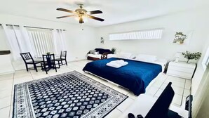 A bedroom with a bed, a desk, a chair, a ceiling fan, and a window with curtains. - Beach Tide Motel - #5 Studio 1 King bed (Hollywood)