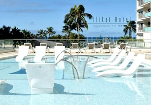 Relax by the pool at Likai Hotel, surrounded by palm trees and a clear sky.