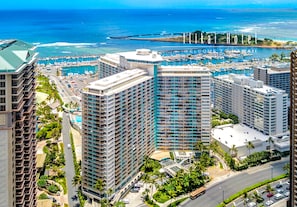 A high-rise hotel with multiple balconies, a marina with boats, and a view of the ocean. - Ocean View Waikiki Luxury Ilikai Hotel~ (Honolulu)