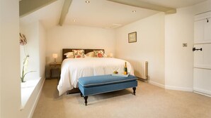 Une chambre à coucher avec un lit, une table de chevet, une commode et une fenêtre agrémentée d’une plante.