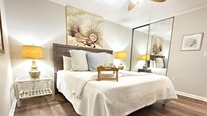 Ein Schlafzimmer mit einem großen Bett, Nachttischen mit Lampen, einem Spiegel und Bildern an der Wand.