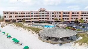 Ein großes Hotel mit mehreren Etagen, einem Poolbereich und einem Strand mit Sonnenschirmen.