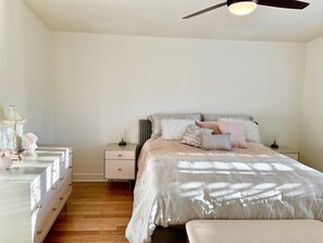 Un dormitorio con cama, mesitas de noche, cómoda y ventilador de techo.