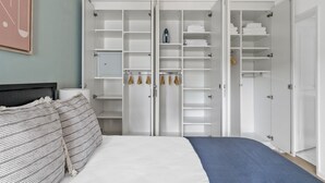 Ein Schlafzimmer mit einem Bett, einem Kleiderschrank mit vielen Regalen und einem blauen Teppich.