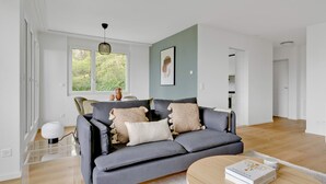 Ein modernes Wohnzimmer mit einem grauen Sofa, einem runden Couchtisch und einer gläsernen Vitrine.