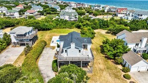 A residential area with houses, a large house with a deck, and a view of the ocean.