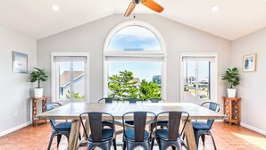 A dining area with a large table, six chairs, and a ceiling fan.