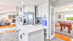 A spacious kitchen with white cabinets, a central island, and a built-in refrigerator.