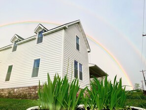 A white two-story house with a stone foundation and a sloped roof. - Newly renovated early 1900’s farmhouse (Birch Tree)