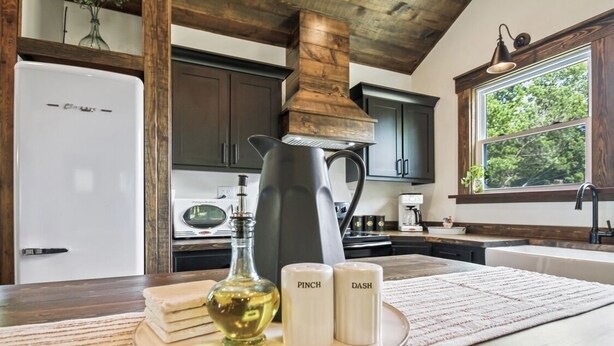A kitchen with dark wooden cabinets, a white refrigerator, a coffee maker, and a window with a view of trees.