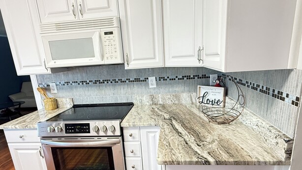A kitchen with white cabinets, a stainless steel range, a microwave, and a tiled backsplash. - Water front, river views, fishing from backyard, Large yard to enjoy. (Hampton)