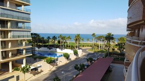 Un hotel a più piani con piscina, palme e vista sull'oceano.