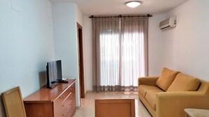 Un soggiorno con divano, televisore su un mobile in legno e finestra con tende.