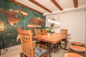 Uma sala de jantar com mesa de madeira, cadeiras e um mural de um mapa-múndi na parede.