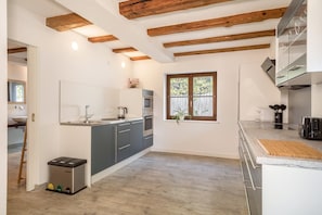 Une cuisine moderne avec des poutres en bois, un évier, une cuisinière et une fenêtre donnant sur l’extérieur.
