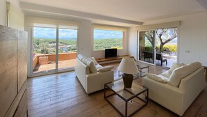 A spacious living room with a large sliding glass door leading to a balcony, a flat-screen TV, and a coffee table. - Holiday rental villa with swimming pool in Begur, Centre (Begur)