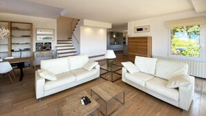 A modern living room with two white sofas, a coffee table, and a staircase leading to a kitchen. - Holiday rental villa with swimming pool in Begur, Centre (Begur)