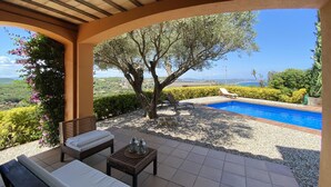 A covered outdoor area with a pool, lounge chairs, and a view of the landscape. - Holiday rental villa with swimming pool in Begur, Centre (Begur)