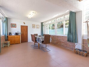 Un coin repas comprenant une table et des chaises, un meuble en bois et une fenêtre avec des rideaux.