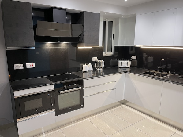 A modern kitchen with a black countertop, stainless steel appliances, and a window above the sink.