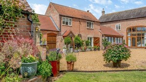 A traditional brick house with a tiled roof, a well-maintained garden, and a gravel driveway. - Paddock Cottage - Thorpe Arnold, Melton Mowbray (Melton Mowbray)