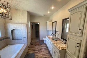 A bathroom with a bathtub, vanity, and a fireplace.