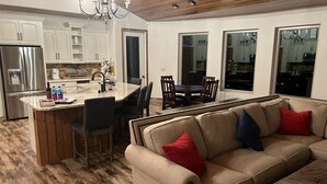 Eine moderne Küche mit weißen Schränken, einem Edelstahl-Kühlschrank und einem Essbereich mit Holztisch und Stühlen.