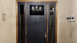 Eine dunkle Holztür mit Glasfenster und einer darüber hängenden Chandelierleuchtre.