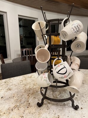 Eine Küche mit einer Kaffeestation, inklusive eines Muggestells mit mehreren Tassen und einem Teekessel.