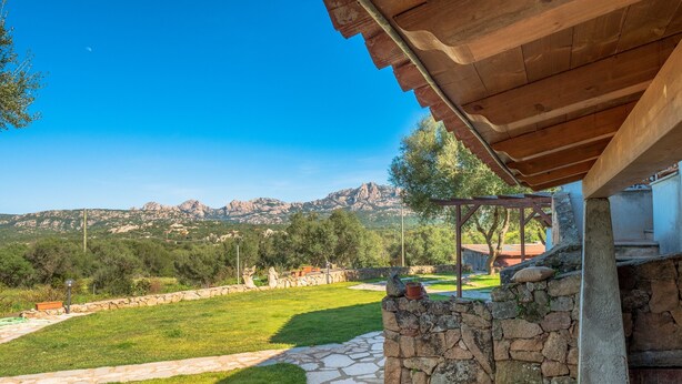 A stone pathway leading to a wooden pergola with a view of mountains.