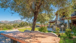 A patio with a bench, a stone wall, and a view of mountains.