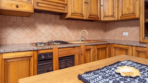 A kitchen with wooden cabinets, a granite countertop, a gas stove, a dishwasher, and a sink.
